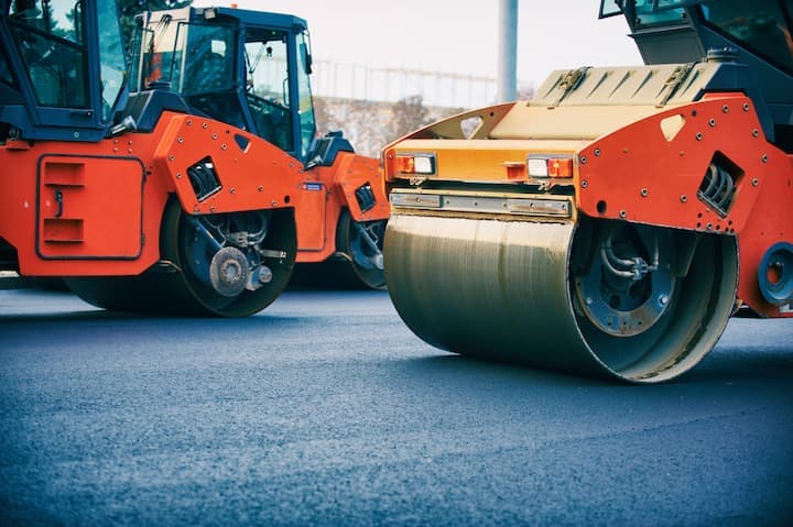 A steam roller sits on fresh asphalt.