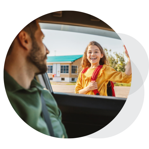 A girl waves to her dad as he drops her off at school.