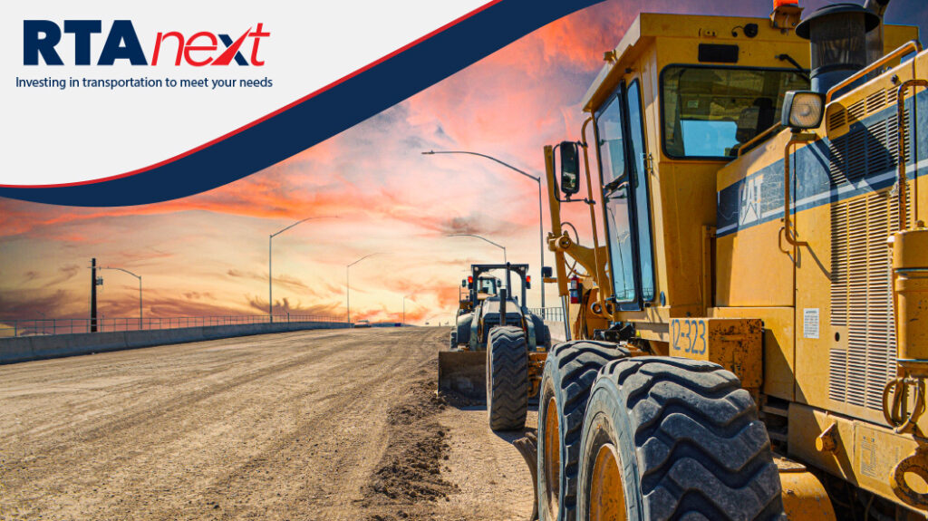 Two excavator vehicles work on level the base of a yet to be paved road.