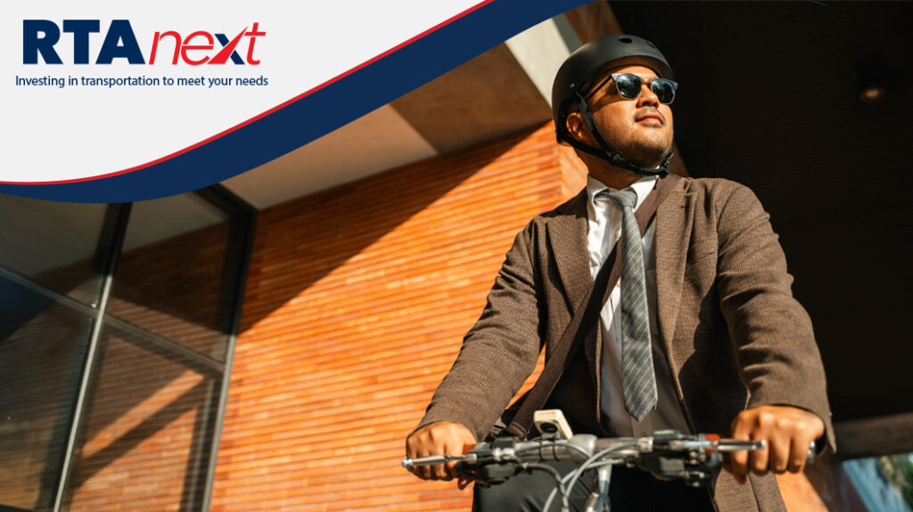A man wearing a helmet and sunglasses pulls up to an office building on his bicycle.
