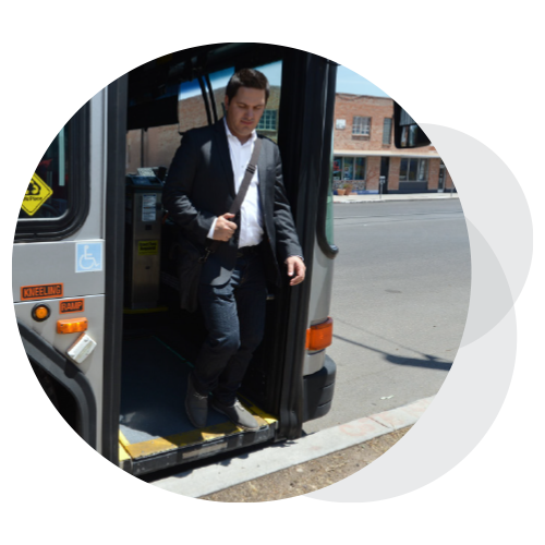 A man in a suit stepping off a bus.